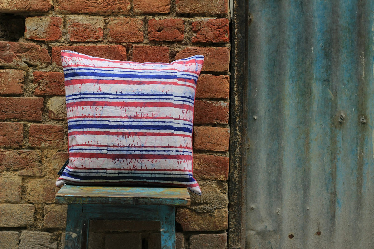 Striped cushion on a blue stool against a brick wall