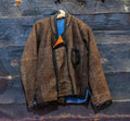 Handwoven wool jacket hanging on a wooden wall