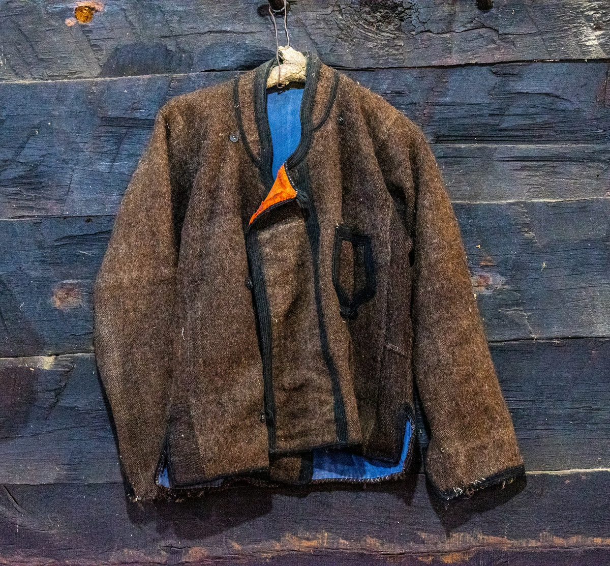 Handwoven wool jacket hanging on a wooden wall