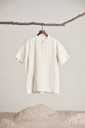 Off-white short sleeve shirt hanging from a branch