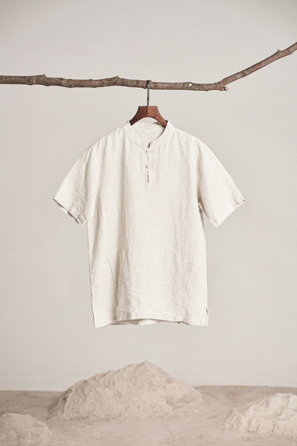 Off-white short sleeve shirt hanging from a branch